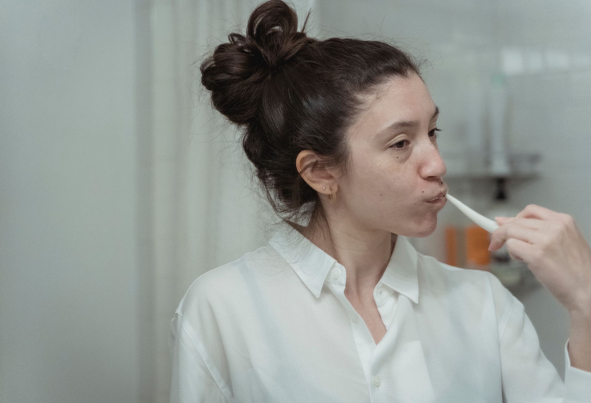 A woman brushes her teeth in the bathroom as part of her daily oral hygiene routine.
