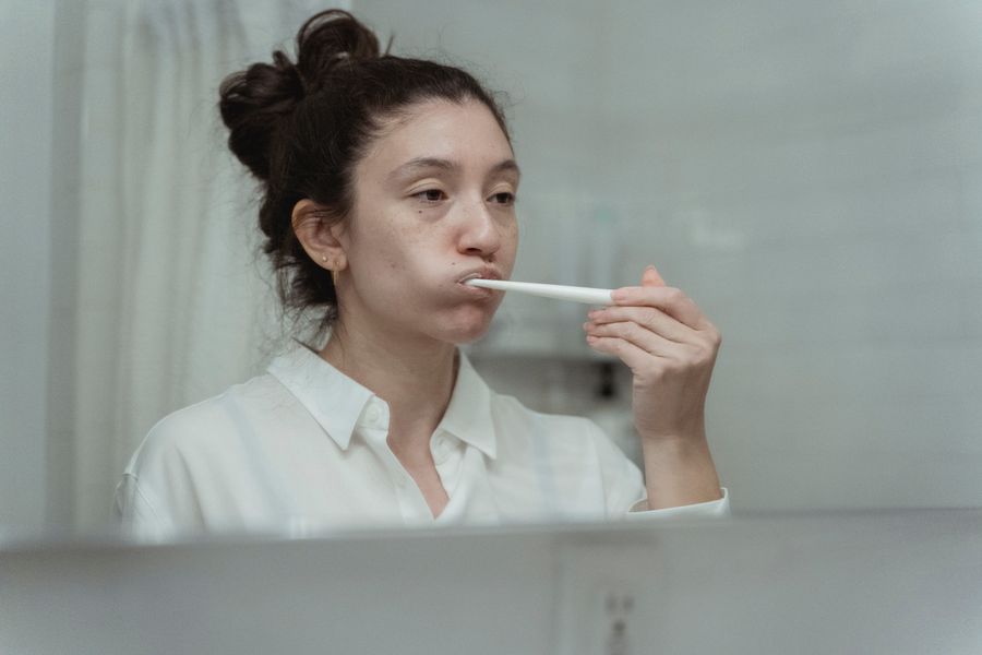 Side view of a woman brushing her teeth, focusing on dental care and hygiene.