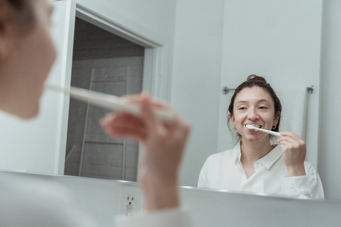 Free Reflection On Mirror of a Woman Brushing Her Teeth Stock Photo