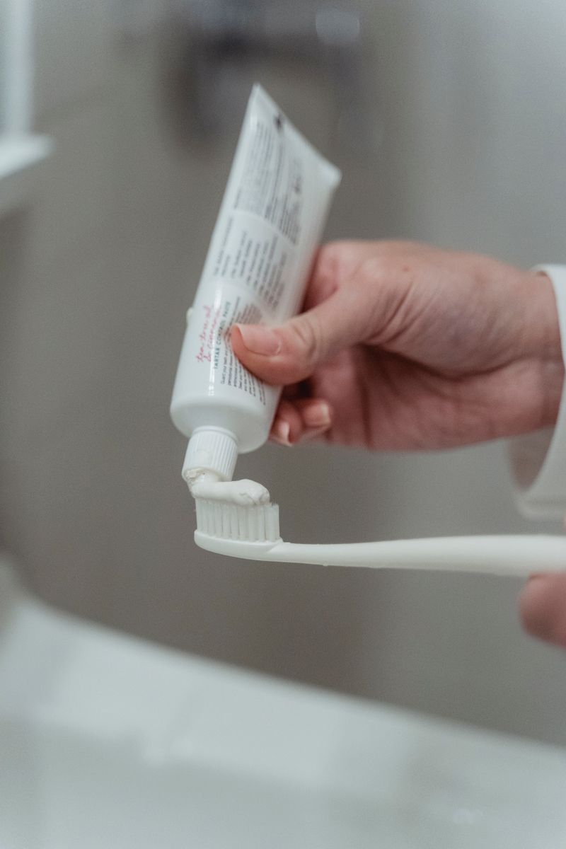 Personne appliquant du dentifrice sur une brosse à dents pour bien se brosser les dents
