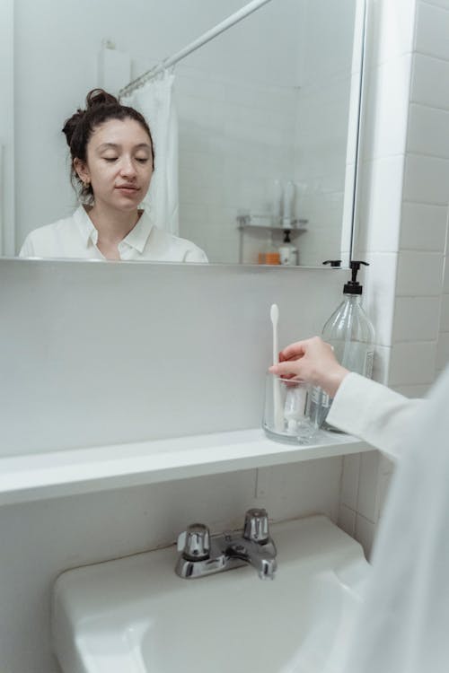 Woman Putting Her Toothbrush In A Glass