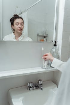 Woman practices morning dental hygiene in a contemporary bathroom setting, focusing on health and cleanliness.