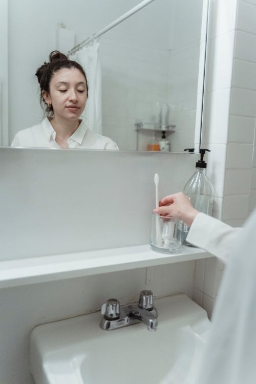 Free Woman practices morning dental hygiene in a contemporary bathroom setting, focusing on health and cleanliness. Stock Photo