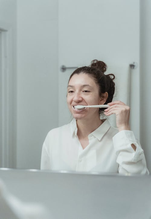 Reflection of a Woman In the Mirror Brushing Her Teeth