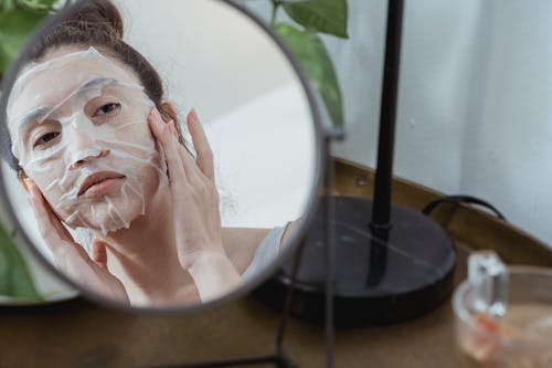 Woman with Cosmetic Mask Looking at a Mirror