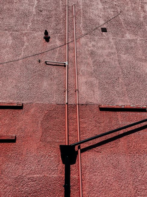 From below of aged building with tall thin pipes on shabby rough wall on sunny day