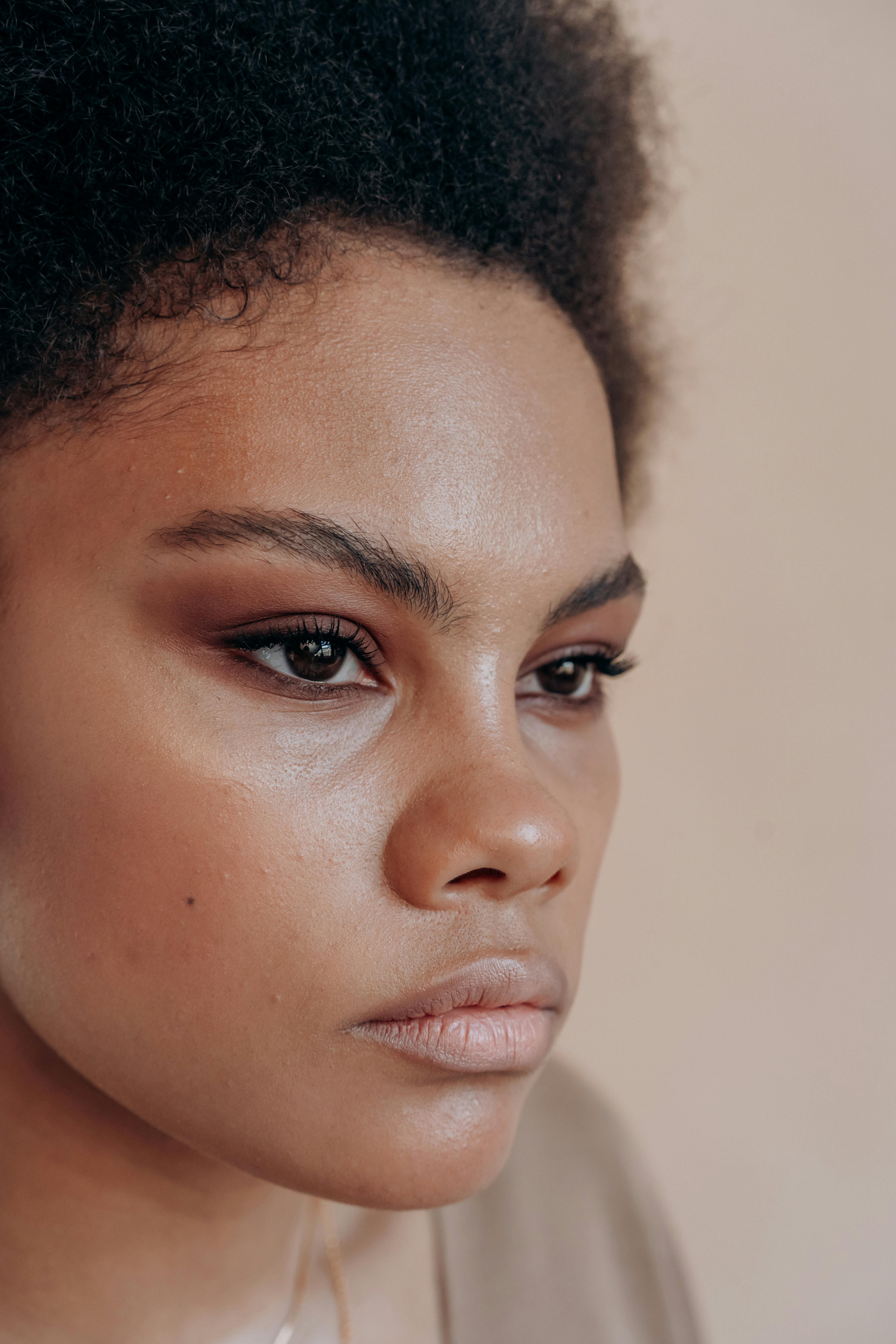 Close-up portrait of a woman with natural makeup in soft lighting, conveying elegance and introspection.
