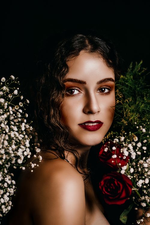 Free Sophisticated portrait of a woman with red roses and white flowers on a dark background. Stock Photo