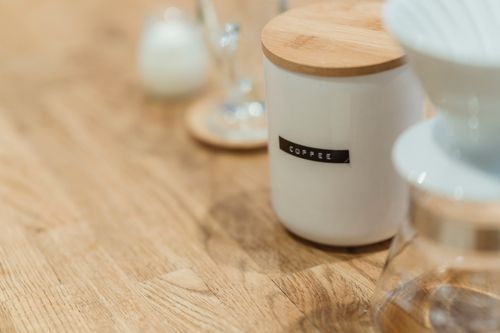 Free Close-up of a ceramic coffee jar with a wooden lid on a table, perfect for stylish kitchen storage. Stock Photo