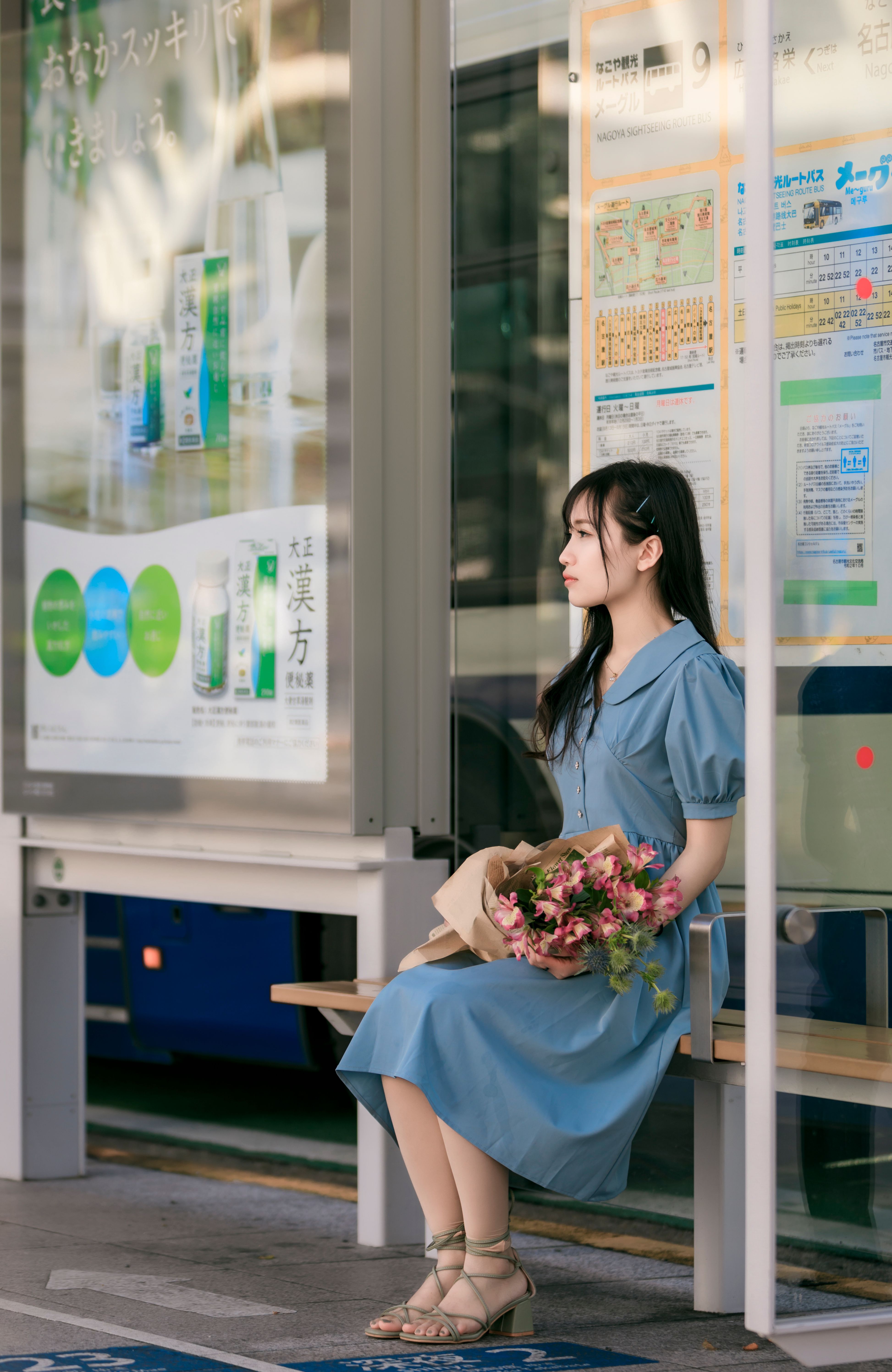 Woman in Blue Dress Sitting On A Wooden Bench With A Bouquet of Flowers ...