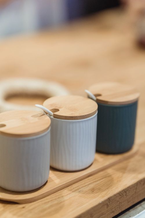 Free Three ceramic pots with wooden lids on a wooden tray, perfect for kitchen seasoning storage. Stock Photo