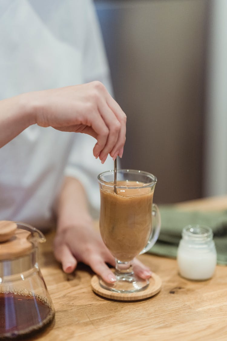 Hand Holding Spoon In Coffee Glass