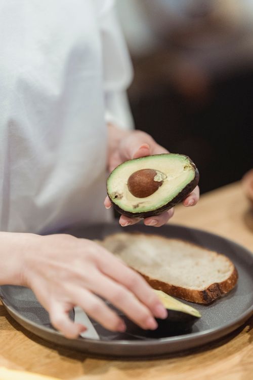 Free Close-up of hands slicing avocado on bread for a healthy snack. Stock Photo