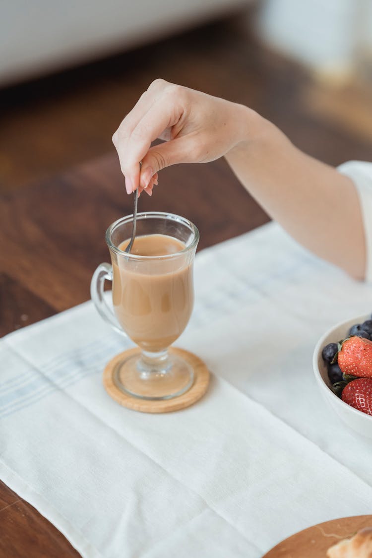 Female Hand With Spoon In Coffee Glass