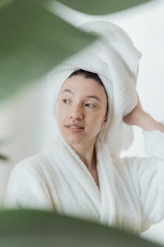 Tranquil scene of a woman in a bathrobe with a towel turban, surrounded by plants.