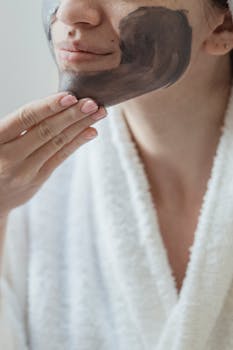 Close-up of a woman applying a skincare facial mask in a relaxing spa setting.