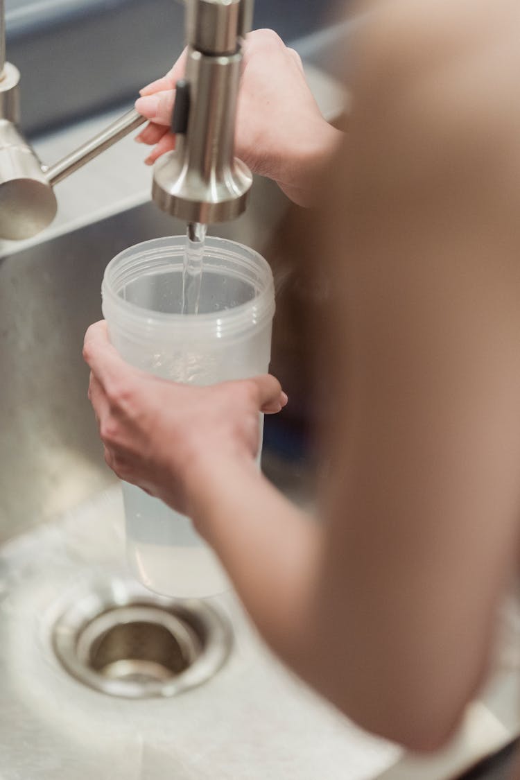 Close Up Of A Woman Pouring Water Into A Bottle