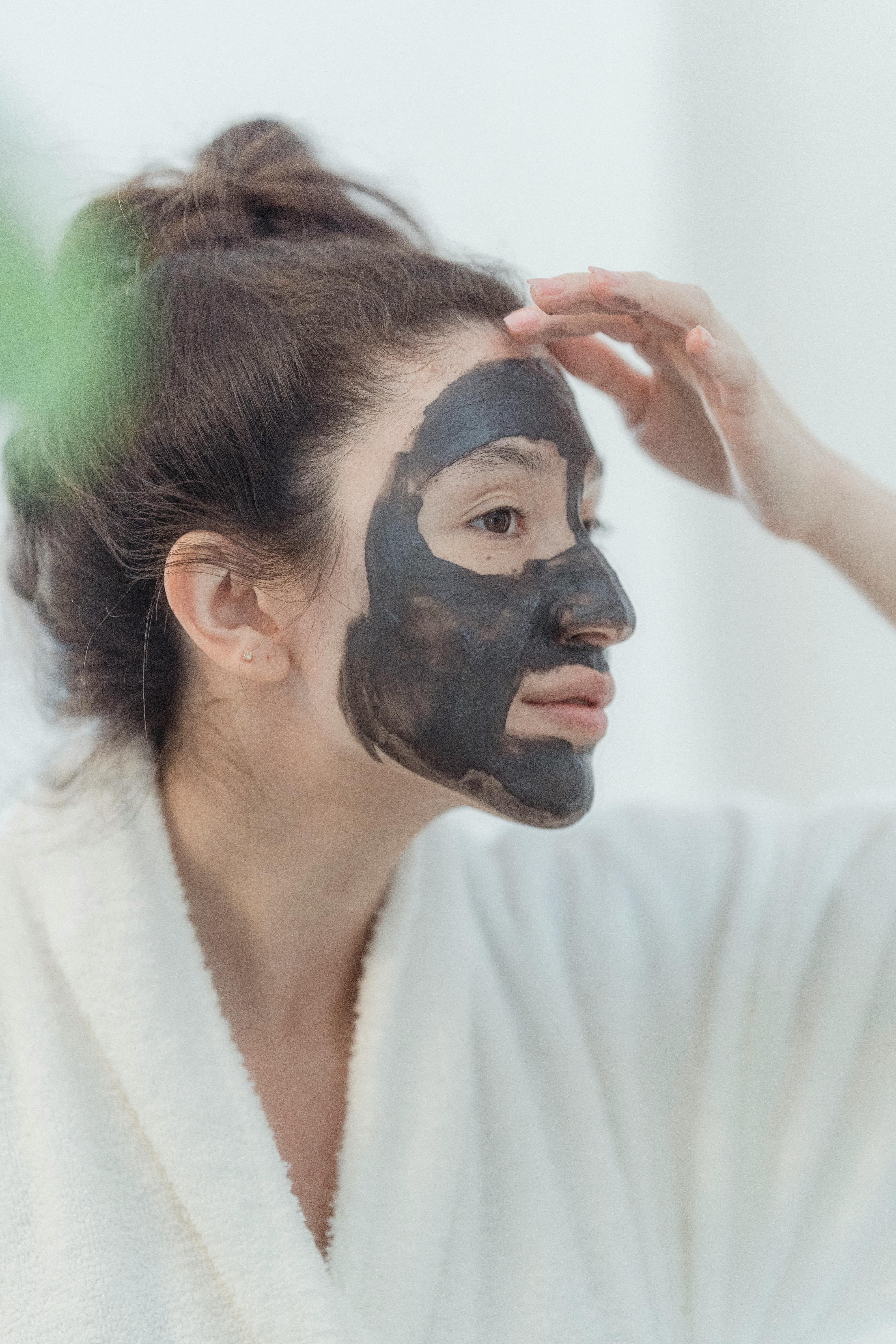 woman in bathrobe with beauty mask on face