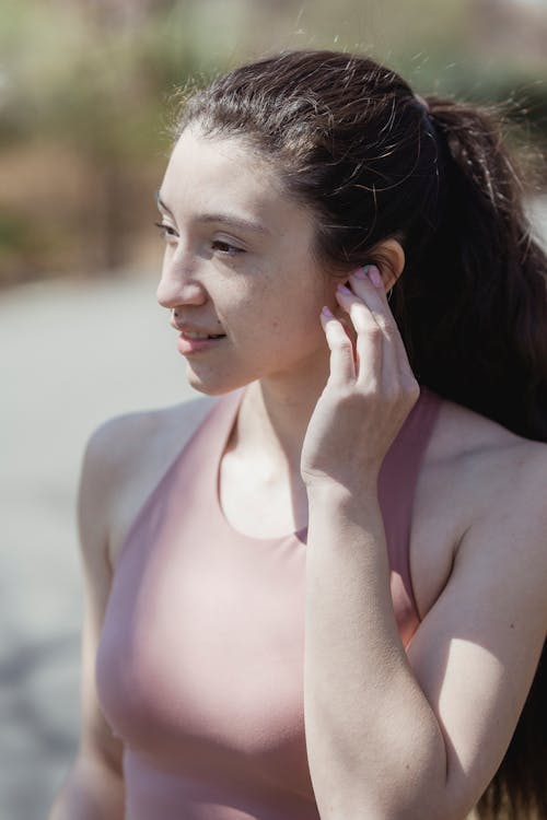 Woman in Pink Tank Top with Hand on Ear