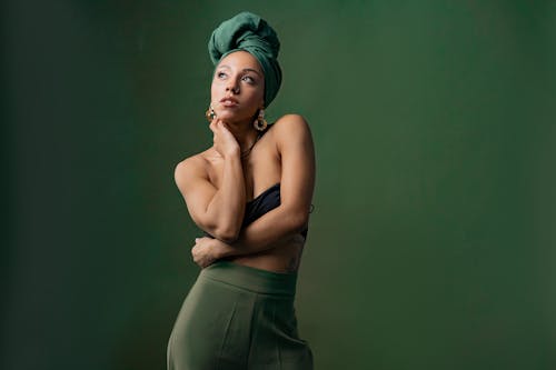 A Woman in Tube Top and Green Headscarf Looking Up with Her Hand on Her Neck