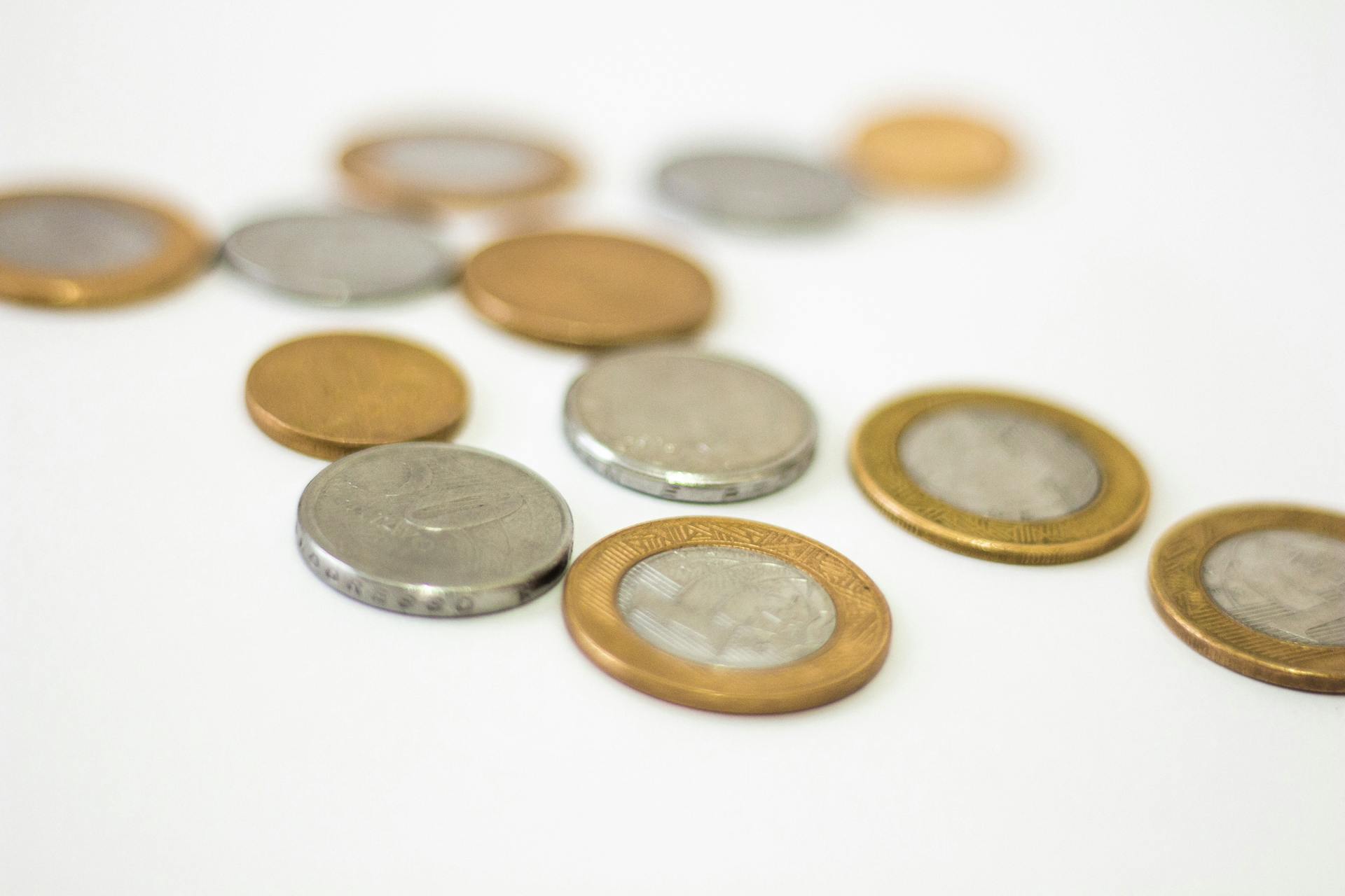 Collection of assorted gold and silver coins scattered on a white surface, offering a modern financial concept.