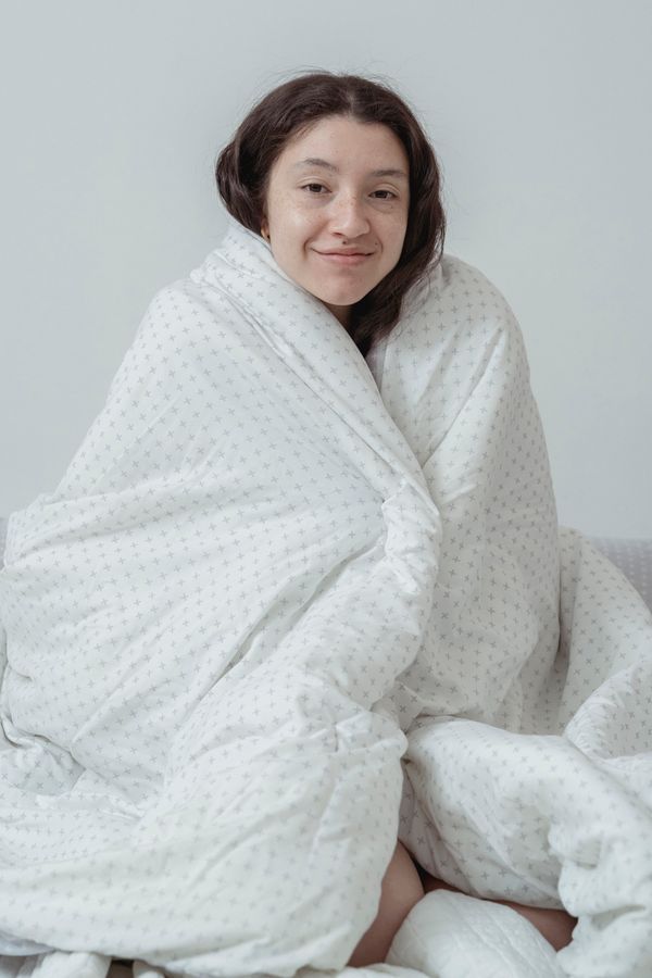 Woman wrapped in a blanket feeling cold at home