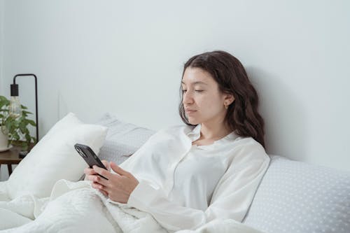 Free A Woman Holding ang Looking at Her Smartphone  Stock Photo