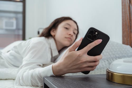 Free Close up of a Woman in a Bed Looking at Mobile Phone Stock Photo
