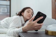 Close up of a Woman in a Bed Looking at Mobile Phone