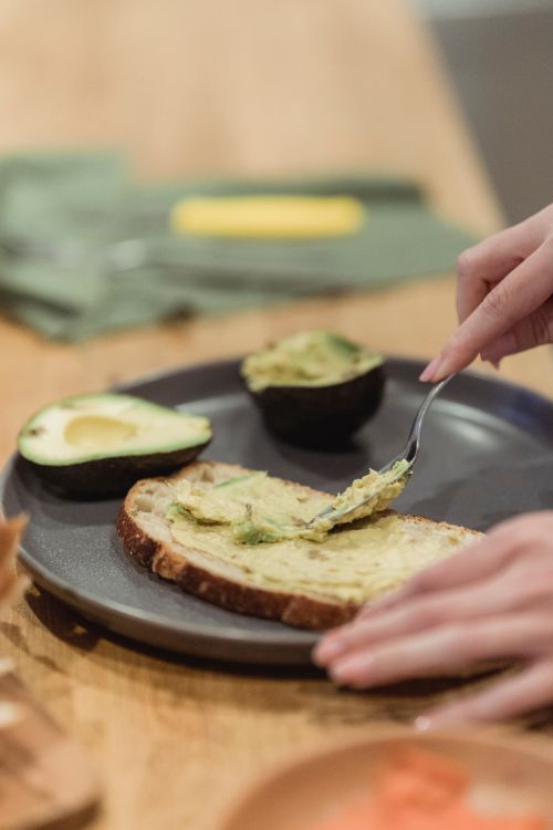 Free Hands spreading avocado on toast in a home kitchen setting. Perfect for healthy lifestyle concepts. Stock Photo