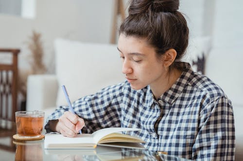 Woman Drinking Tea Writing in Notebook