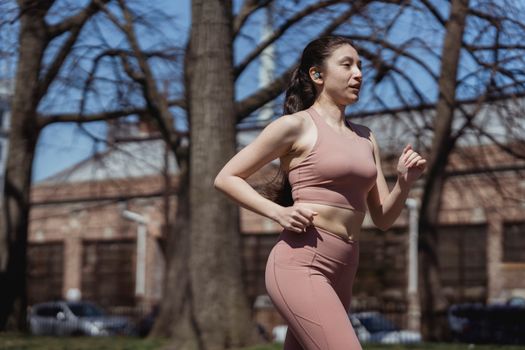 Fit woman jogging in sportswear on a sunny day, embracing a healthy lifestyle.