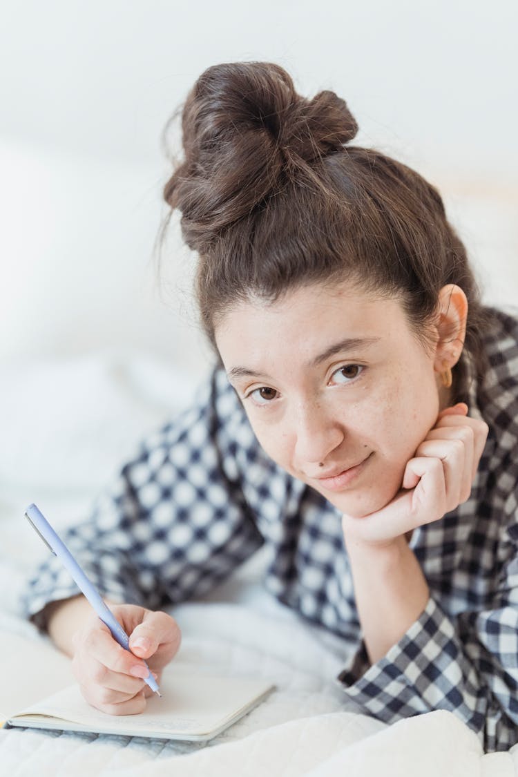 Woman Lying On Bed And Writing Journal