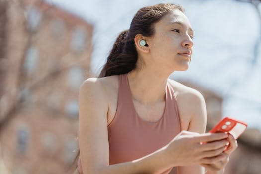 Young woman in a tank top outdoors, looking afar while holding a smartphone.