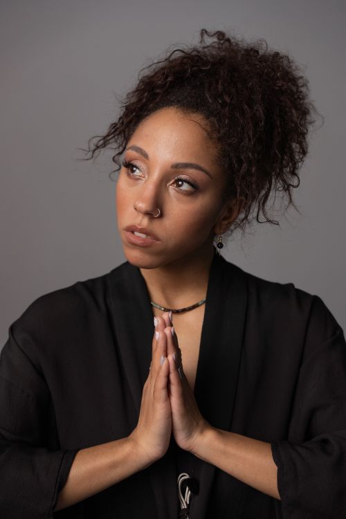Free Graceful woman in a black robe with folded hands against a gray background. Stock Photo