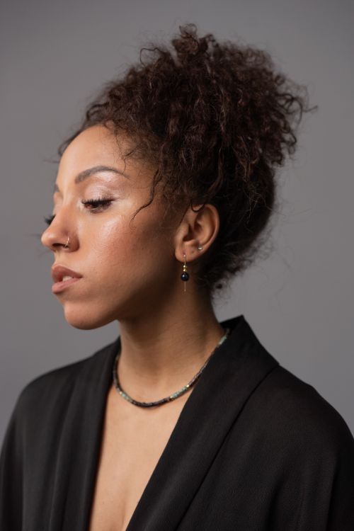Free Close-up profile portrait of a stylish woman with afro hair, captured in a studio setting. Stock Photo