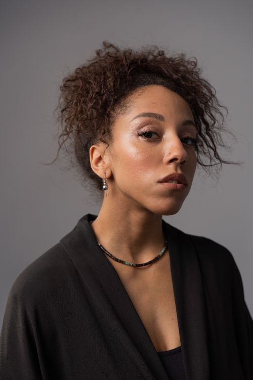 Free Close-up portrait of a woman with afro hair in a studio setting, showing elegance and confidence. Stock Photo