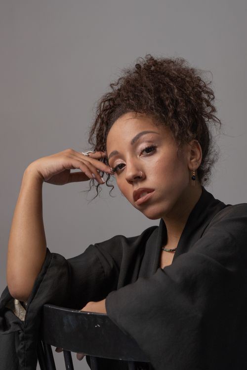 Free Close-up studio portrait of a beautiful woman with curly hair wearing black attire. Stock Photo