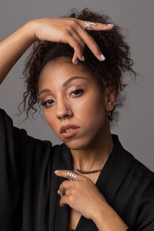 Free Close-up studio portrait showcasing an elegant woman with afro hair and stylish jewelry posing gracefully. Stock Photo