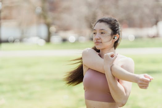 A young woman in activewear stretching outdoors, promoting fitness and healthy lifestyle.