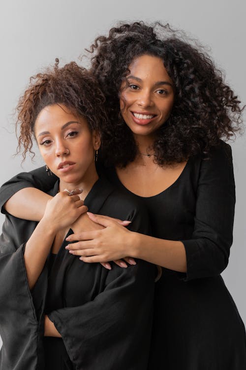 Free Two Afro-Haired Women in Black Robes Hugging Stock Photo