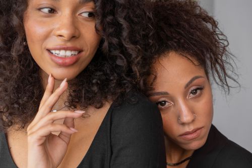 Free A close-up studio portrait showcasing two stylish women with afro hair, highlighting beauty and fashion. Stock Photo