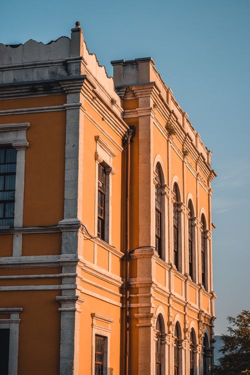 Free A beautifully lit historic building exterior with classical architectural details at sunset. Stock Photo