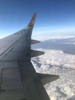 Wing view from an airplane over a snow-covered landscape in Türkiye, capturing sky and clouds.