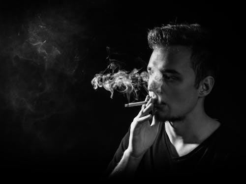 A Man in V-neck Shirt Smoking a Cigarette