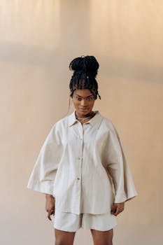 Stylish woman with dreadlocks in a beige outfit posing confidently indoors.