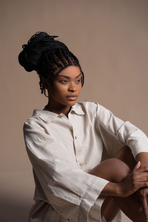 Free Portrait of a stylish woman in a studio setting, showcasing braided hair and a relaxed look. Stock Photo