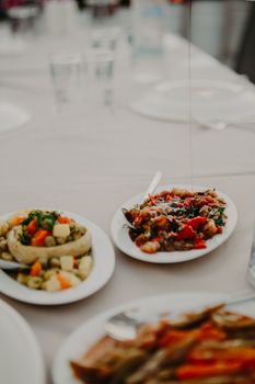 White table served with assorted delicious dishes on white round plates and glasses of water in restaurant