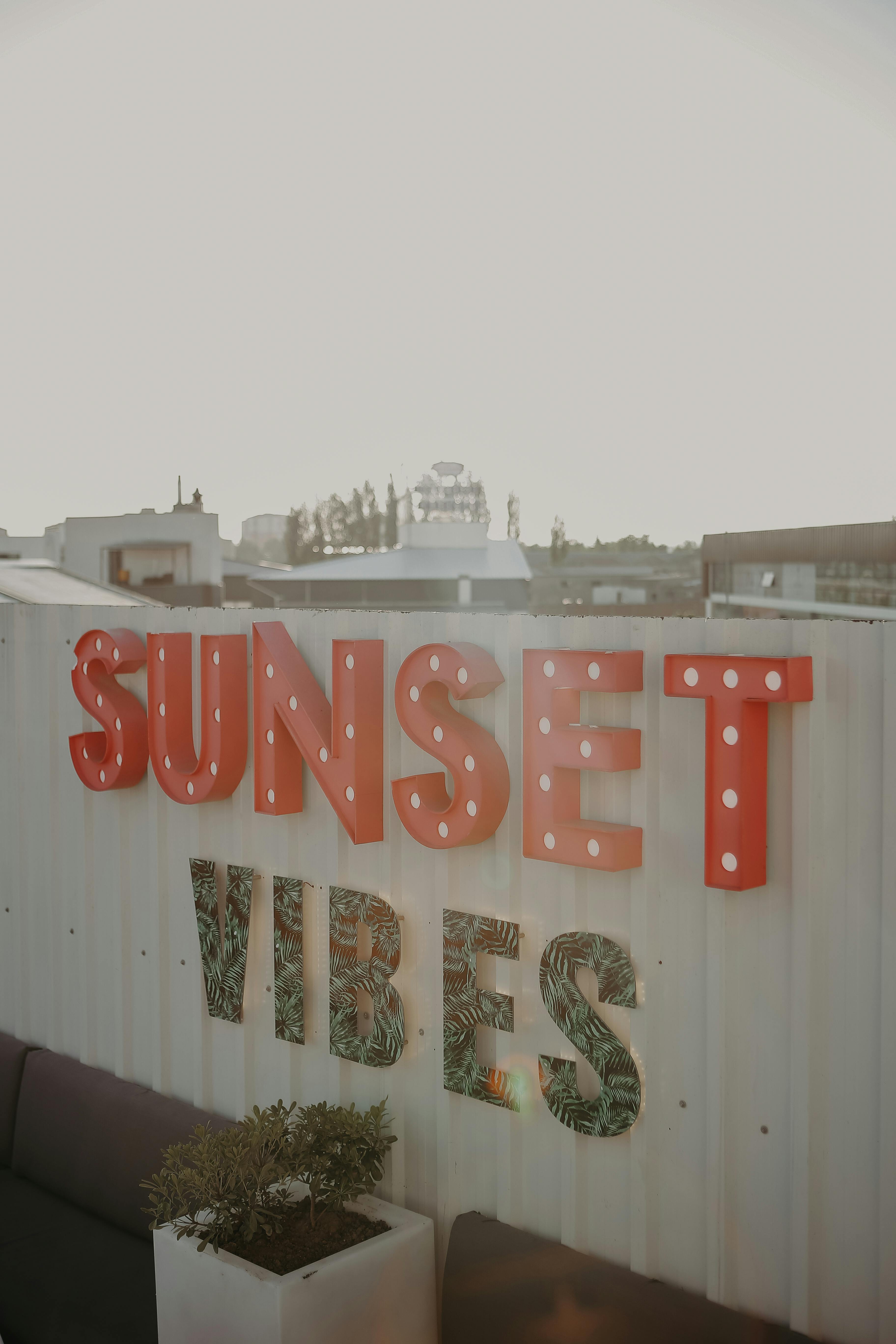 Artistic rooftop decor with 'Sunset Vibes' sign capturing downtown ambiance at dusk.