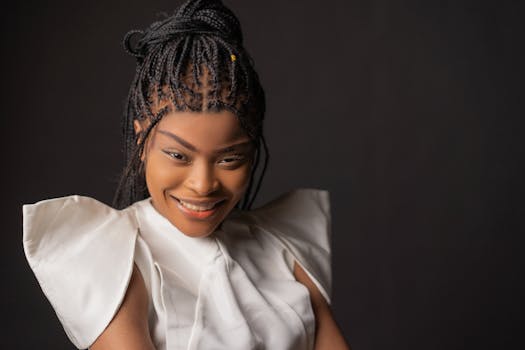 Portrait of a smiling woman with braided hair in a studio setting.